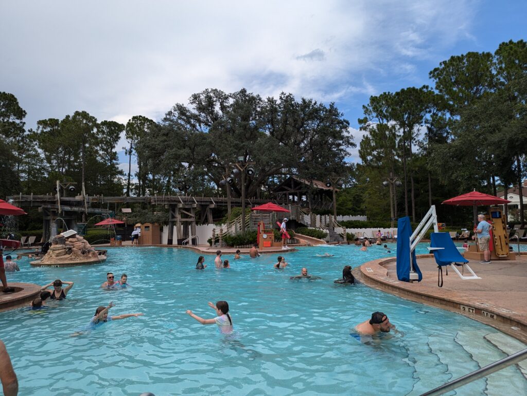 Guests swimming at the rustic Ol' Man Island recreation and pool area at Port Orleans Riverside. 
